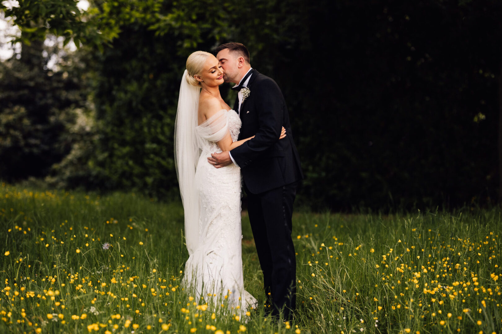 A bride and groom embracing in a field of wildflowers.