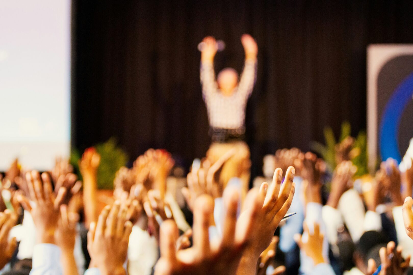 A large room with people raising their hands.