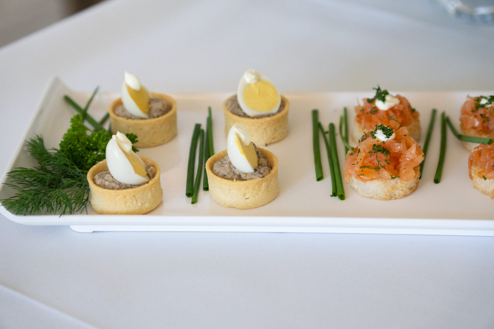 A white square plate with various hors d'oeuvres.