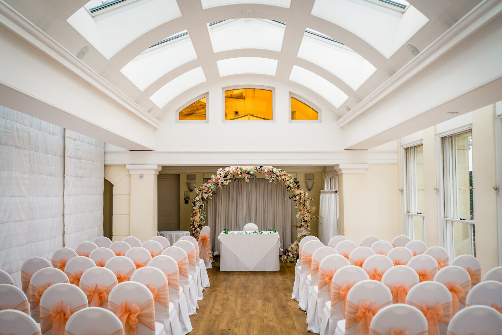 A spacious room with an arched roof and rows of chairs covered in cloth.