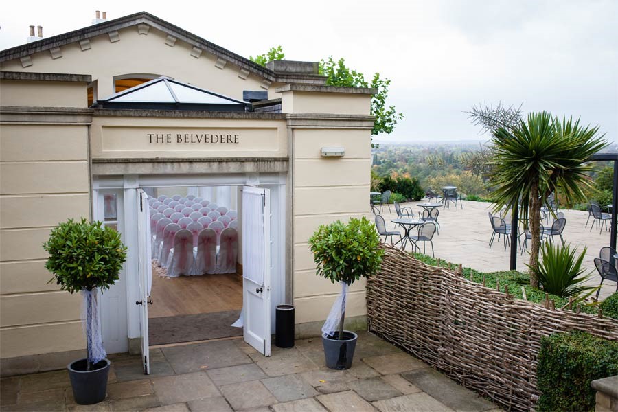 An exterior view of the The Belvedere with potted plants at either side of the entrance.