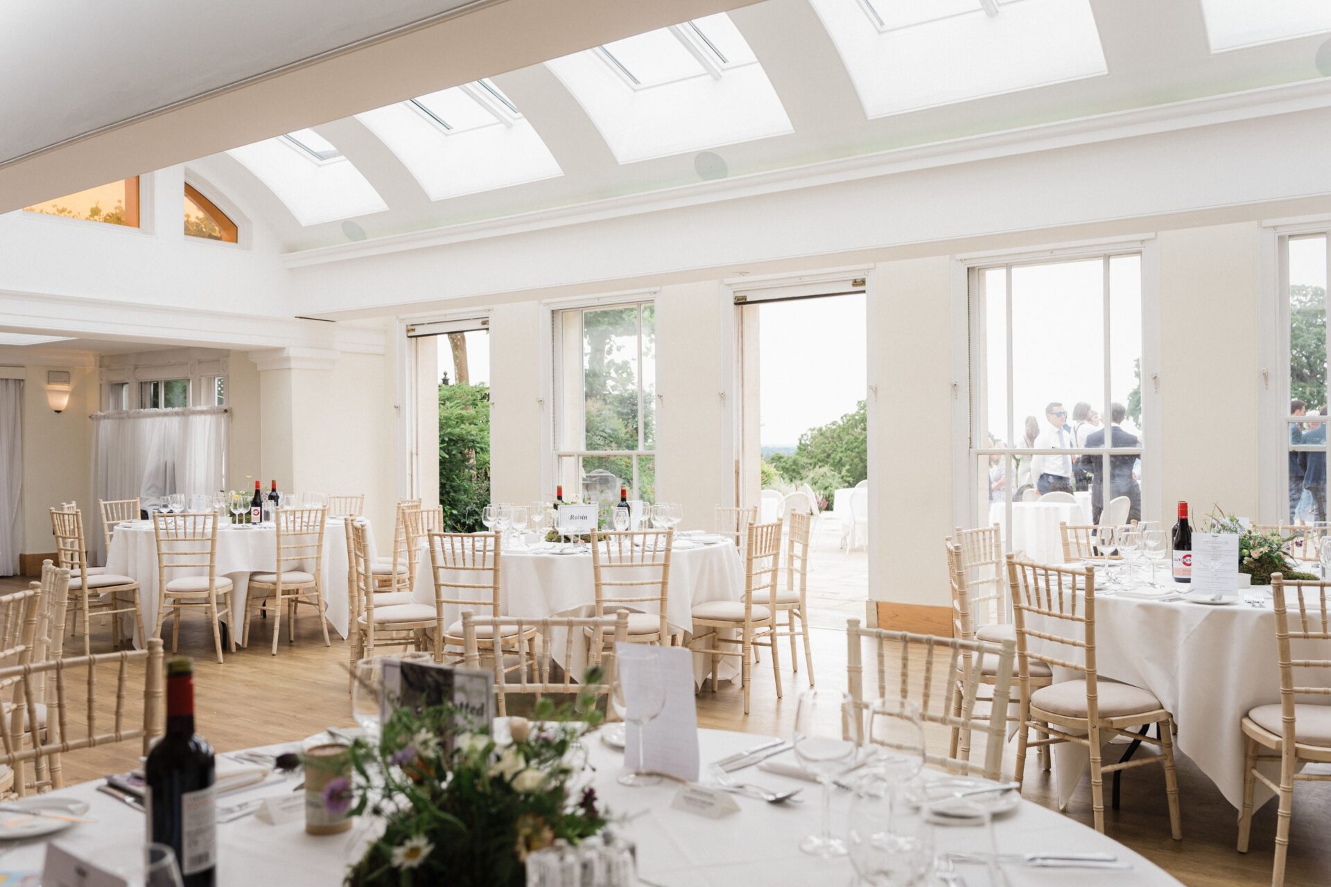 Round white tables and light wooden chairs in a bright room.