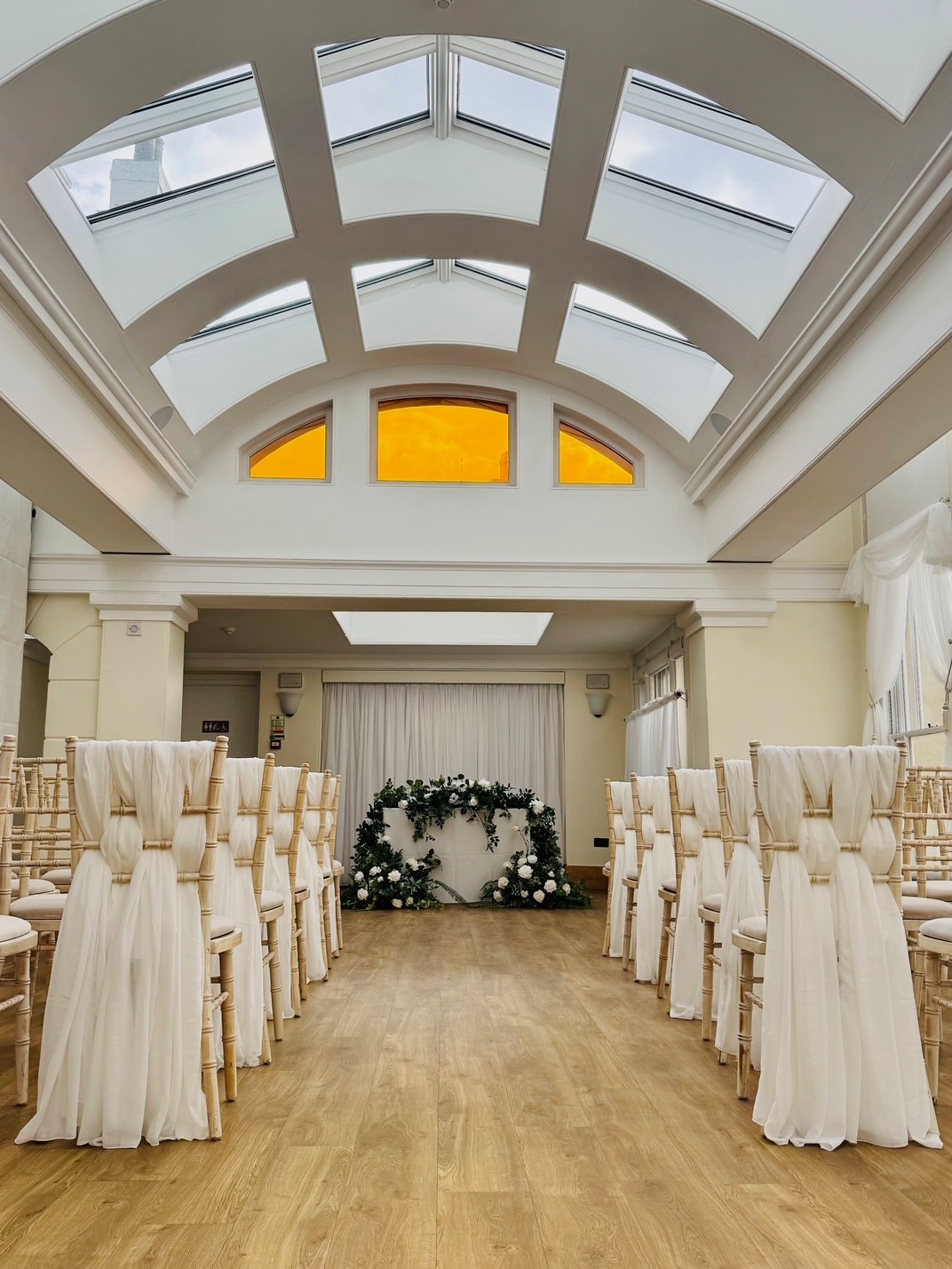 Rows of chairs with white material in a long white room.