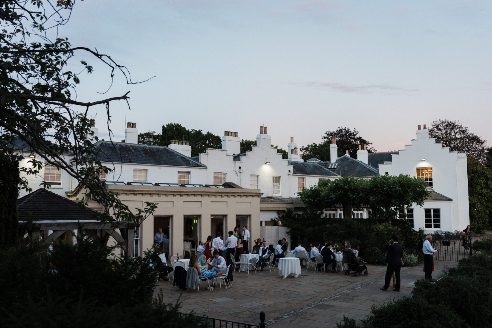A large white building with a patio at dusk.